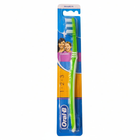 An Oral-B Classic toothbrush in its original blue, yellow, and orange retail blister packaging, shown against a plain white background.